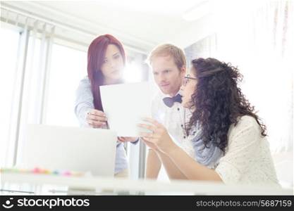 Businesspeople discussing over photograph in creative office