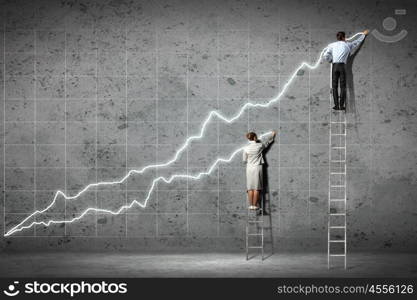 businesspeople drawing diagrams on wall. businesspeople standing on ladder drawing diagrams and graphs on wall