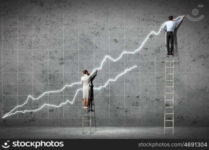 businesspeople drawing diagrams on wall. businesspeople standing on ladder drawing diagrams and graphs on wall