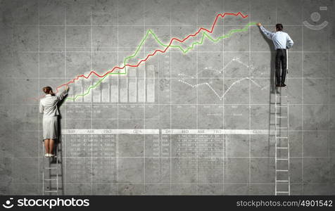 businesspeople drawing diagrams on wall. businesspeople standing on ladder drawing diagrams and graphs on wall