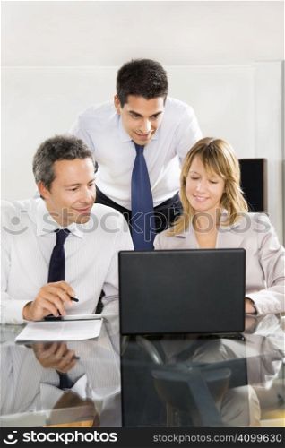Businesspeople looking at laptop in meeting room.