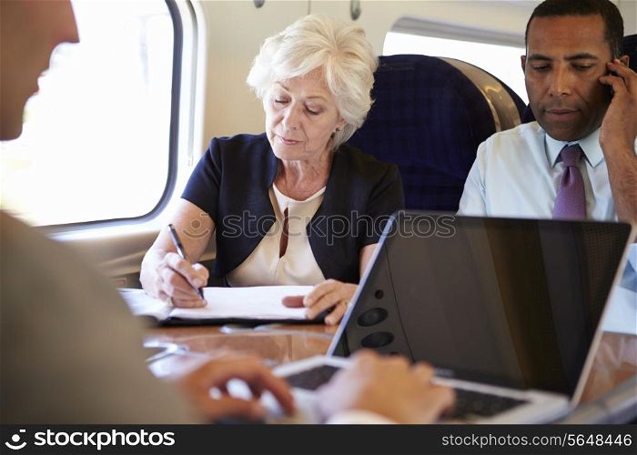 Businesspeople On Train Using Digital Devices