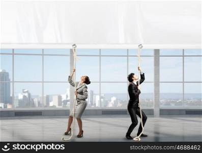 Businesspeople pulling banner. Young businessman and businesswoman in office and blank banner. Place for text