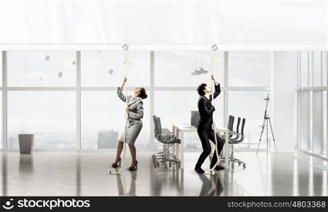 Businesspeople pulling banner. Young businessman and businesswoman in office and blank banner. Place for text