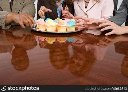 Businesspeople reaching for cupcakes