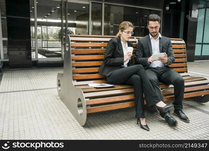 businesspeople sitting bench looking mobile phone