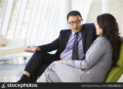Businesspeople Sitting On Sofa In Modern Office