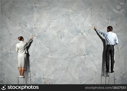 businesspeople standing on ladder drawing diagrams and graphs on wall