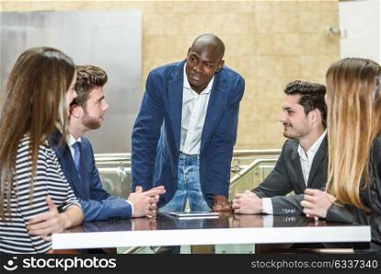 Businesspeople, teamwork. Group of multiethnic busy people working in an office with a black businessman as a leader of the group