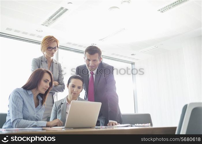 Businesspeople using laptop in conference room