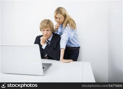 Businesspeople using laptop together at desk in office
