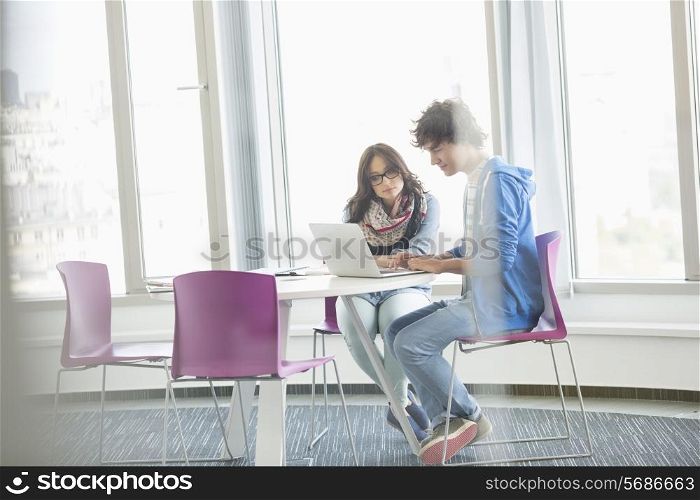 Businesspeople using laptop together in creative office