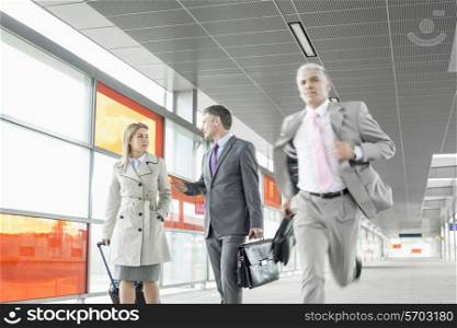 Businesspeople walking while male colleague running in railroad station