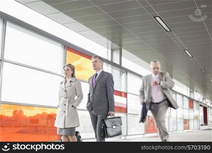 Businesspeople walking while male colleague running in railroad station