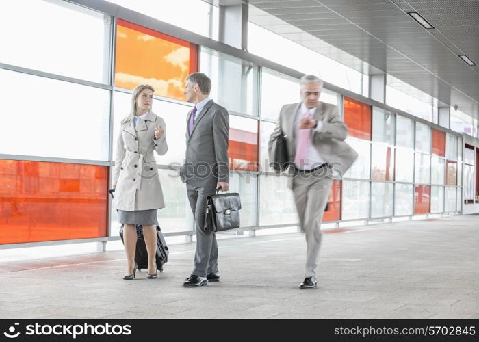 Businesspeople walking while male colleague rushing in railroad station