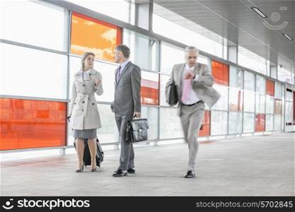 Businesspeople walking while male colleague rushing in railroad station