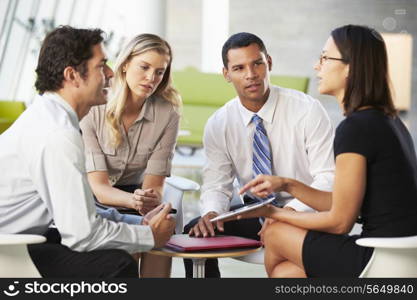 Businesspeople With Digital Tablet Having Meeting In Office