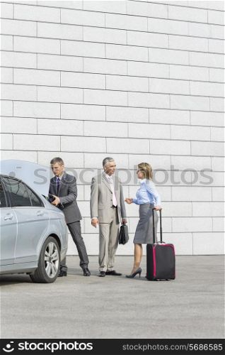 Businesspeople with luggage communicating outside car on street