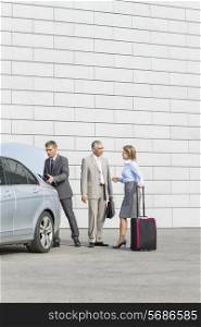 Businesspeople with luggage communicating outside car on street