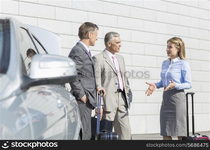 Businesspeople with luggage discussing outside car
