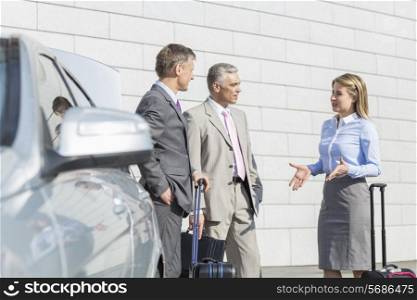 Businesspeople with luggage discussing outside car