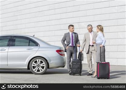 Businesspeople with luggage discussing outside car on street