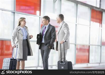 Businesspeople with luggage talking on railroad platform