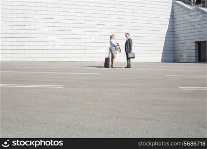 Businesspeople with luggage talking on street