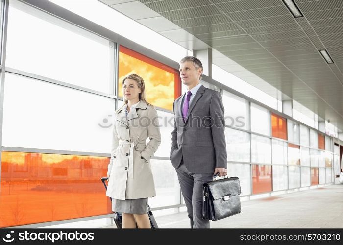 Businesspeople with luggage walking in railroad station