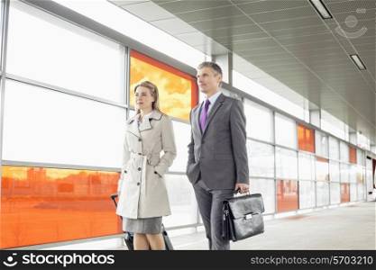 Businesspeople with luggage walking in railroad station