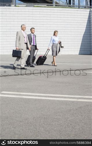 Businesspeople with luggage walking on street