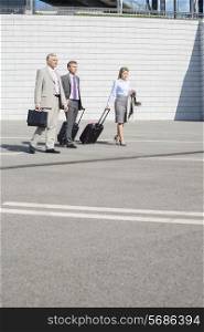Businesspeople with luggage walking on street