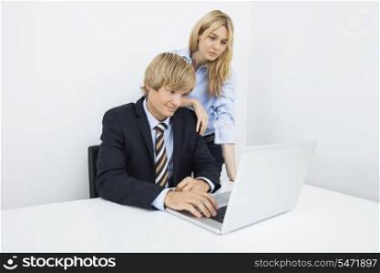 Businesspeople working on laptop at desk in office