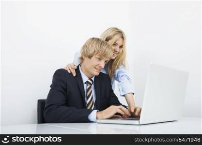 Businesspeople working on laptop at desk in office