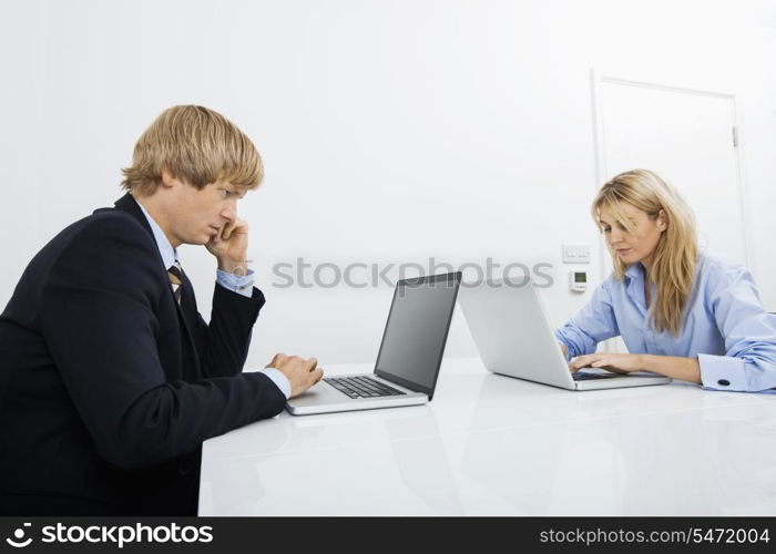 Businesspeople working on laptops in office
