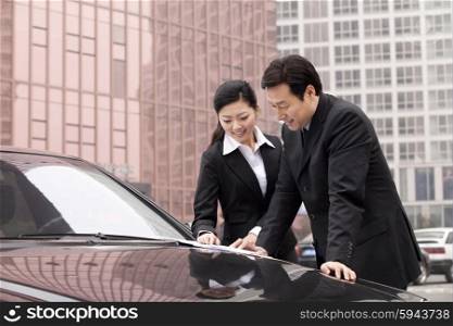 Businesspeople working outdoors on car