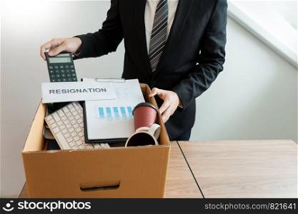 Businessperson carrying packing personal company on brown cardboard Box and resignation letters for quit or change of job leaving the office, unemployment, resigned concept.