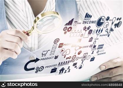 Businessperson examining business plan. Close view of businesswoman looking through magnifying glass