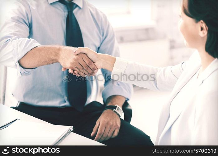 businesss and office concept - businessman and businesswoman shaking hands in office