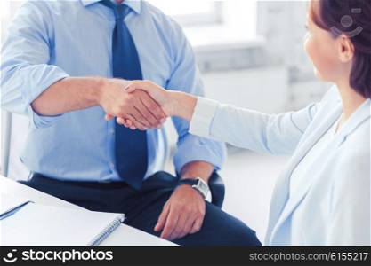 businesss and office concept - businessman and businesswoman shaking hands in office. business people shaking hands in office