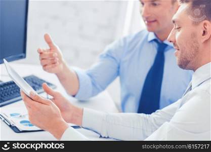 businesss and office concept - businessmen with notebook and tablet pc discussing graphs on meeting. businessmen with notebook and tablet pc