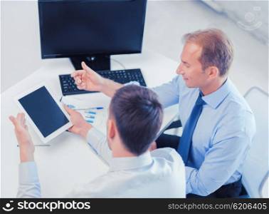 businesss and office concept - businessmen with notebook and tablet pc discussing graphs on meeting. businessmen with notebook and tablet pc