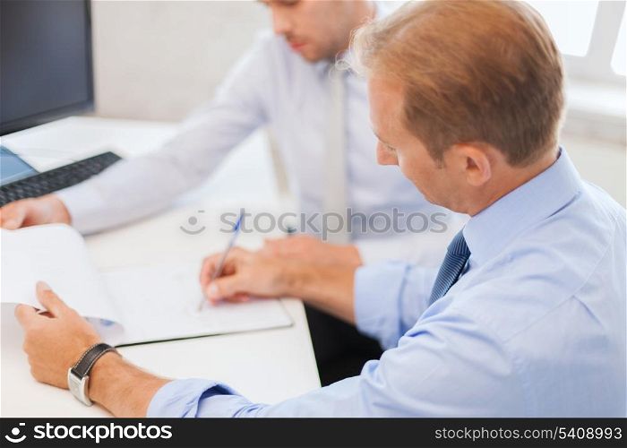 businesss and office concept - businessmen with notebook discussing graphs on meeting