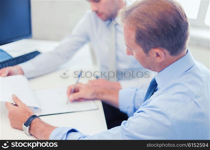businesss and office concept - businessmen with notebook discussing graphs on meeting. businessmen with notebook on meeting