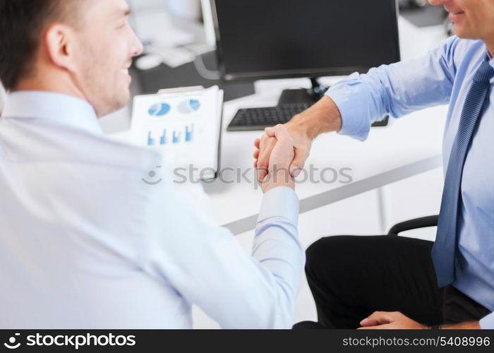 businesss and office concept - two businessmen shaking hands in office