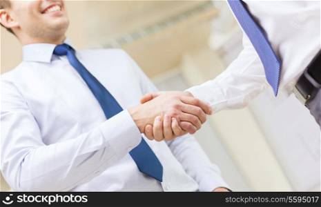 businesss and office concept - two businessmen shaking hands in office