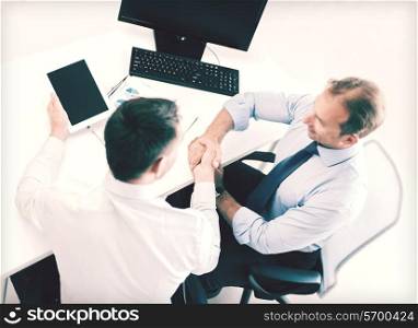 businesss and office concept - two businessmen shaking hands in office