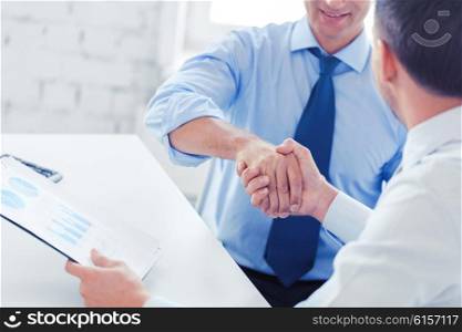 businesss and office concept - two businessmen shaking hands in office. businessmen shaking hands in office