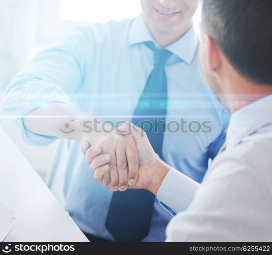 businesss and office concept - two businessmen shaking hands in office. businessmen shaking hands in office