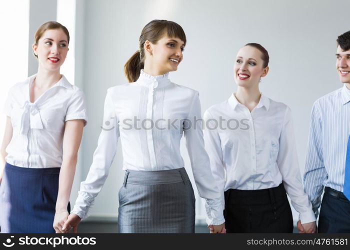 Businessteam holding hands. Image of four businesspeople standing in row. Partnership concept